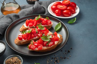 Gri-mavi arka planda domates, fesleğen ve peynirli İtalyan bruschetta. Yan görünüm, kopyalamak için boşluk.