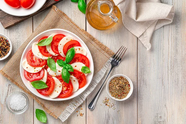Italiensk Kaprissallad Med Tomater Mozzarellaost Och Basilika Tallrik Beige Träbakgrund — Stockfoto
