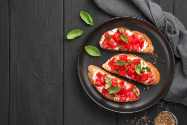 Siyah arka planda domates, tereyağı, fesleğen ve peynirli Üst görünüm, alanı kopyala.