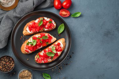 Siyah tabakta domates, peynir ve fesleğen. İtalyan mezesi. Domatesli kızarmış ekmek..