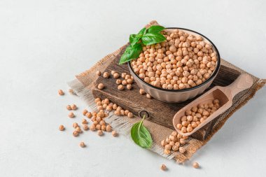 Gri bir arka planda kahverengi bir kasedeki çiğ, kuru nohut ve kopyalamak için yer var. Yan görüş. Sağlıklı yemek..