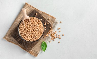 Gri arka planda ahşap bir kepçeyle bir kasede nohut. Üst görünüm, alanı kopyala.