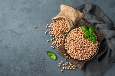 Bir kasede çiğ nohut ve gri-mavi arka planda keten bir çanta. Sağlıklı, organik yiyecekler. Üst görünüm.