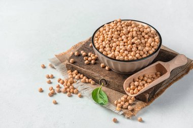 Hafif bir arka planda tahta bir tahtanın üzerinde bir kasede nohut. Yan görüş, kopyalamak için alan. Organik yiyecekler.