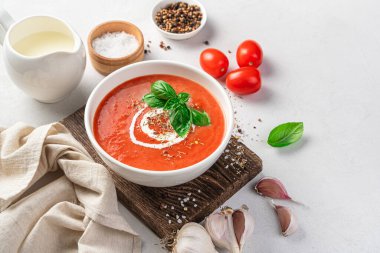 Beyaz kasede domates çorbası. Arka planda hafif malzemelerle birlikte..