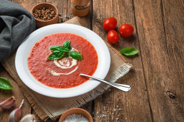 Ahşap arka planda fesleğen ve kremalı ev yapımı domates çorbası. Sağlıklı, organik yiyecekler..