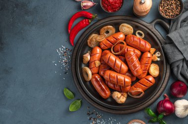Fesleğenli kızarmış sosis, soğan, koyu arkaplanda sarımsak. Fast food. Üst görünüm, kopyalamak için boşluk.