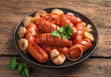 Kızarmış soğanlı sosis, sarımsak ve ahşap arka planda taze maydanoz. Yakın plan..