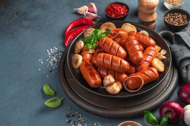 Kızarmış soğanlı sosisler, sarımsak ve koyu arkaplanda taze fesleğen. Yan görüş, kopyalamak için alan. Fast food.