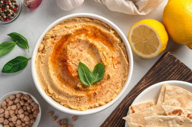 Humus ve malzemeler gri arka planda, yakın plan. Kullanışlı, doğulu bir atıştırmalık, ayrıca meze olarak da kullanılıyor..