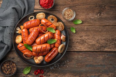 Ahşap zemin üzerinde soğanlı ve sarımsaklı kızarmış sosisler..