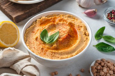 Zeytinyağı ve kırmızı biberli humus. Gri arka planda malzemelerle yakın plan..