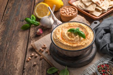 Ahşap arka planda kırmızı biber ve zeytinyağlı geleneksel humus..