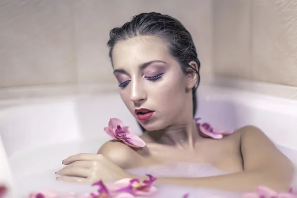 Rubia joven modelo chica en un tanque de leche con flores rojas —  Fotos de Stock