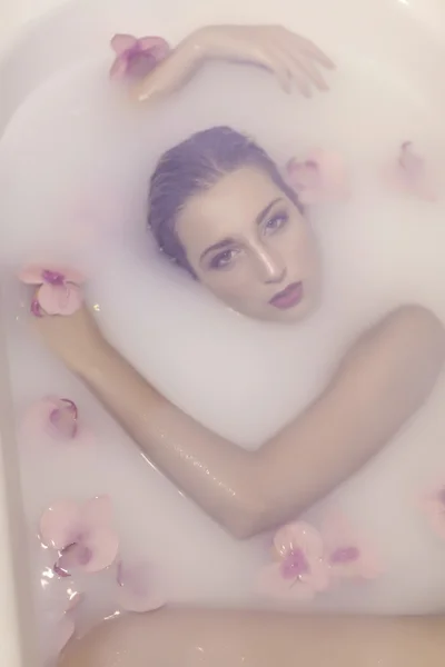 Jovem modelo loira em um tanque de leite com flores vermelhas — Fotografia de Stock