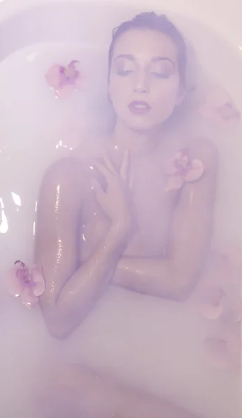 Blond ung modell flicka i en mjölk tank med röda blommor — Stockfoto