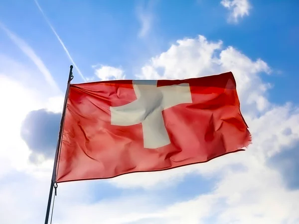 Swiss flag waving over blue sky. High quality photo