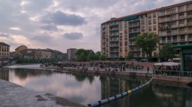 Gün batımında bulutlar Milano 'daki Darsena' nın suyunu yansıtıyor ve insanlar İtalya 'da arka planda yürüyor. Yüksek kalite 4k görüntü