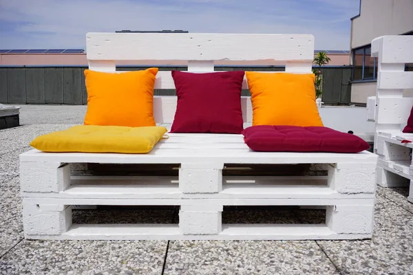 outdoor bench made with pallets and cushions on a terrace. High quality photo