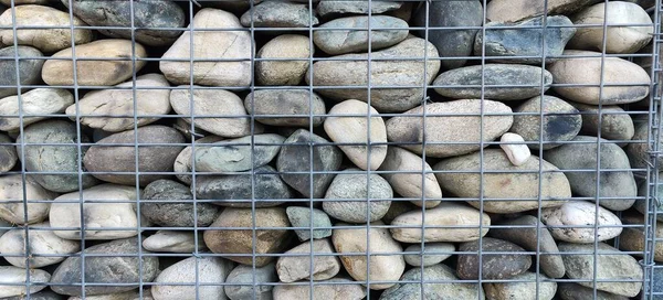 wall of river stones in metal cage. High quality photo