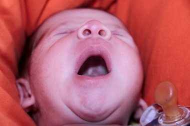 Yeni doğmuş bebek kanepenin üzerinde ağzı açık esniyor. Yüksek kalite fotoğraf