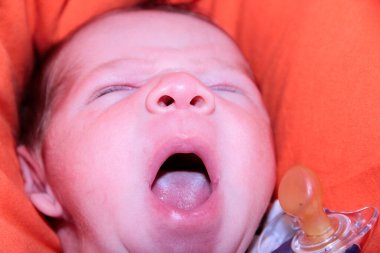 Yeni doğmuş bebek kanepenin üzerinde ağzı açık esniyor. Yüksek kalite fotoğraf