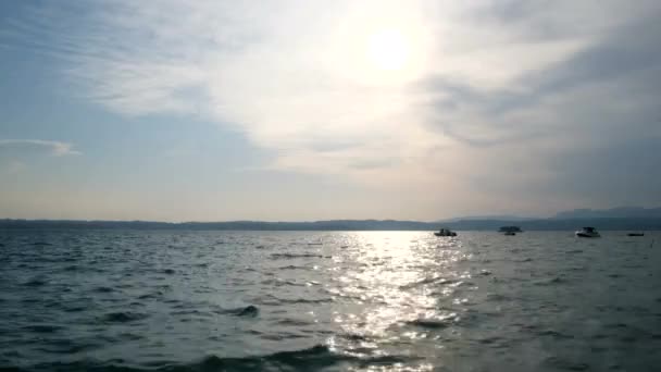 Båtar vid Gardasjön vid solnedgången med sol reflekterande på vatten, Italien — Stockvideo