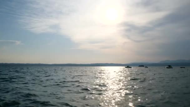 Barcos no Lago de Garda ao pôr do sol com sol refletindo sobre a água, Itália — Vídeo de Stock