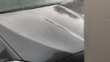 Bir arabanın kaputuna dolu yağıyor.