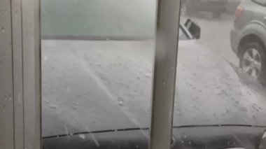 Bir arabanın kaputuna dolu yağıyor.