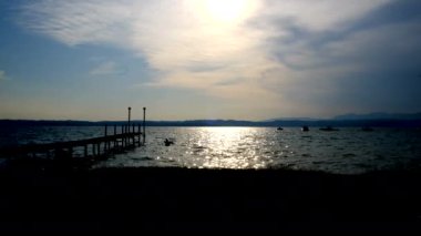Sirmione 'de güzel bir gün batımı ve Garda Gölü' nde iskeleli.