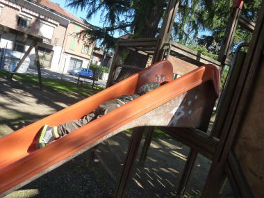 A children lying down in a red slide in a playground of Bibbiano, Reggio Emilia, Italy. High quality photo