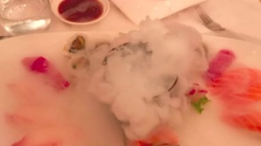 Suşi, kuru buzlu, manzaralı bir tabakta servis edilir.