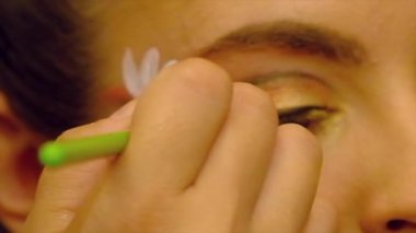 Profesyonel bir sanatçı bir mankenin yüzünü boyuyor.