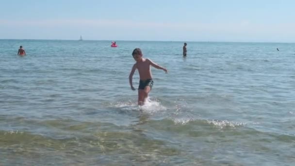 Hermoso niño en el mar juega en las olas en Rímini Riccione Italia — Vídeos de Stock