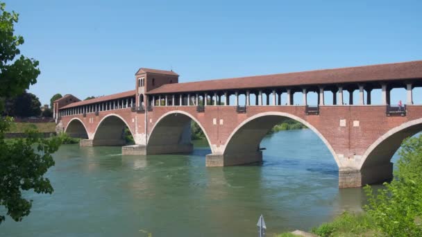 Pavia covered bridge with cars and pedestrians seen the Ticino river. High quality 4k footage