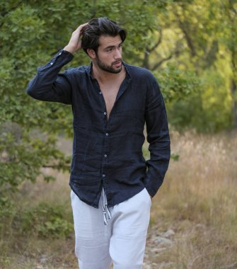 Koyu renk saçlı İtalyan modelin portresi açık renk gözlü ve siyah gömlekli ve ağaçlarda sakallı. Yüksek kalite fotoğraf