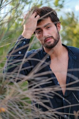 Koyu renk saçlı İtalyan modelin portresi açık renk gözlü ve siyah gömlekli ve ağaçlarda sakallı. Yüksek kalite fotoğraf