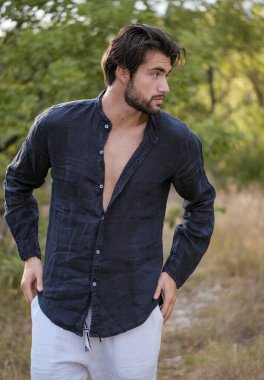 Koyu renk saçlı İtalyan modelin portresi açık renk gözlü ve siyah gömlekli ve ağaçlarda sakallı. Yüksek kalite fotoğraf