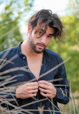 Koyu renk saçlı İtalyan modelin portresi açık renk gözlü ve siyah gömlekli ve ağaçlarda sakallı. Yüksek kalite fotoğraf