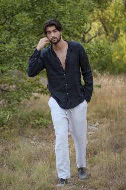 Koyu renk saçlı İtalyan modelin portresi açık renk gözlü ve siyah gömlekli ve ağaçlarda sakallı. Yüksek kalite fotoğraf