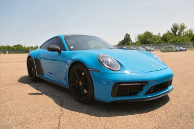 Modena,Italy: 2025 06 08 Low-angle, black and white shot of a modern Porsche 911 992 sportscar parked on asphalt under a bright sun. High quality photo
