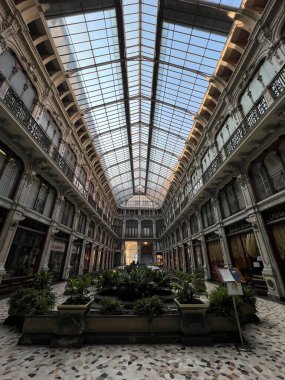 Torino 'daki büyük, tarihi bir alışveriş galerisinin nefes kesici perspektifi, kemerli cam ve demir çatı, süslü balkonlar ve merkezi bir bahçe ekicisi yer alıyor. Yüksek kalite fotoğraf