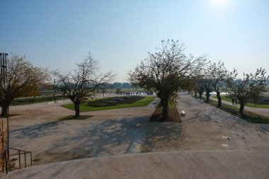 Uzun gölgeler oluşturan sıra sıra ağaçlarla kaplı Reggia di Rivalta bahçesindeki geniş çakıllı gezinti, aydınlık bir günde uzak bir kalabalığın geniş park alanlarının keyfini çıkarmasına yol açıyor. Yüksek kalite fotoğraf