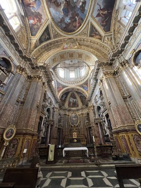 Süslü altın, mermer sütunlar, yüksek tavanlar ve sunağa uzanan kalın desenli mermer döşeme ile zengin bir Barok kilise nav 'ının nefes kesici simetrik görüntüsü. Yüksek kalite fotoğraf