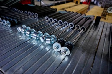 Birkaç parlak metal endüstriyel bileşenin yakın çekim görüntüsü, muhtemelen fındık ya da kollar, bir fabrika ya da depodaki yivli metal bir rafta dizilmişti. Yüksek kalite fotoğraf