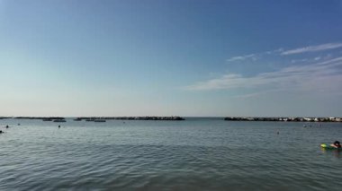 Adriyatik Denizi 'nin Cattolica' daki sakin ve geniş bir fotoğrafı, açık mavi bir gökyüzünün altında açık denize geçiş yolunu tanımlayan iki insan yapımı kaya dalgası içeriyor. Yüksek kalite 4k görüntü