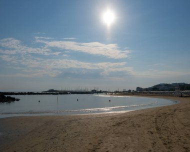 Cattolica 'da sakin bir Adriyatik kıyı şeridi yumuşak dalgalar, kumlu plajlar ve yumuşak bir yaz gökyüzü altında uzak binalar. Yüksek kalite fotoğraf