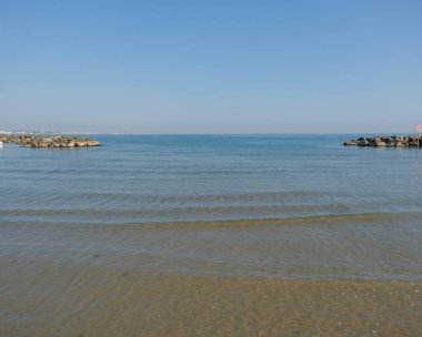 Cattolica 'da sakin bir Adriyatik deniz manzarası. Dalgakıran ve kumlu bir sahil. Parlak mavi bir yaz gökyüzü altında. Yüksek kalite fotoğraf