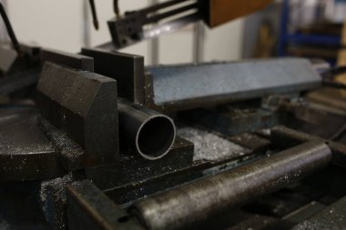 Endüstriyel mengeneye sıkıştırılmış metal boru. Kapalı. Metal talaşlarıyla çevrili yeni kesilmiş tüp görünüyor.